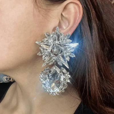 Oversized geometric rhinestone dangle earrings on model.