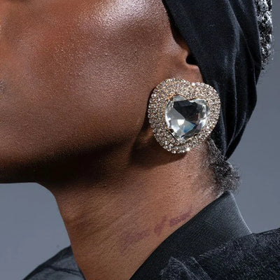 Large crystal heart rhinestone dangle earrings worn on ear.
